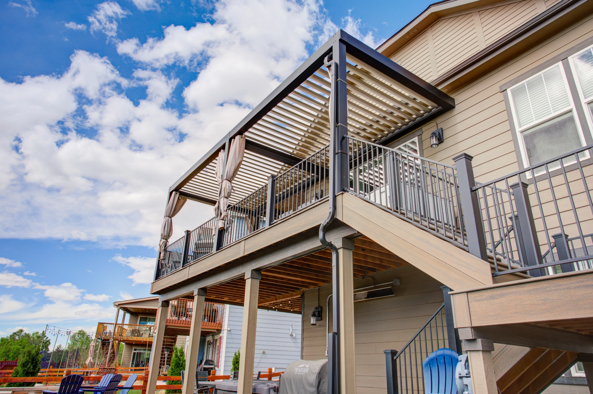 Composite multilevel deck with black aluminum railing and attached louvered pergola